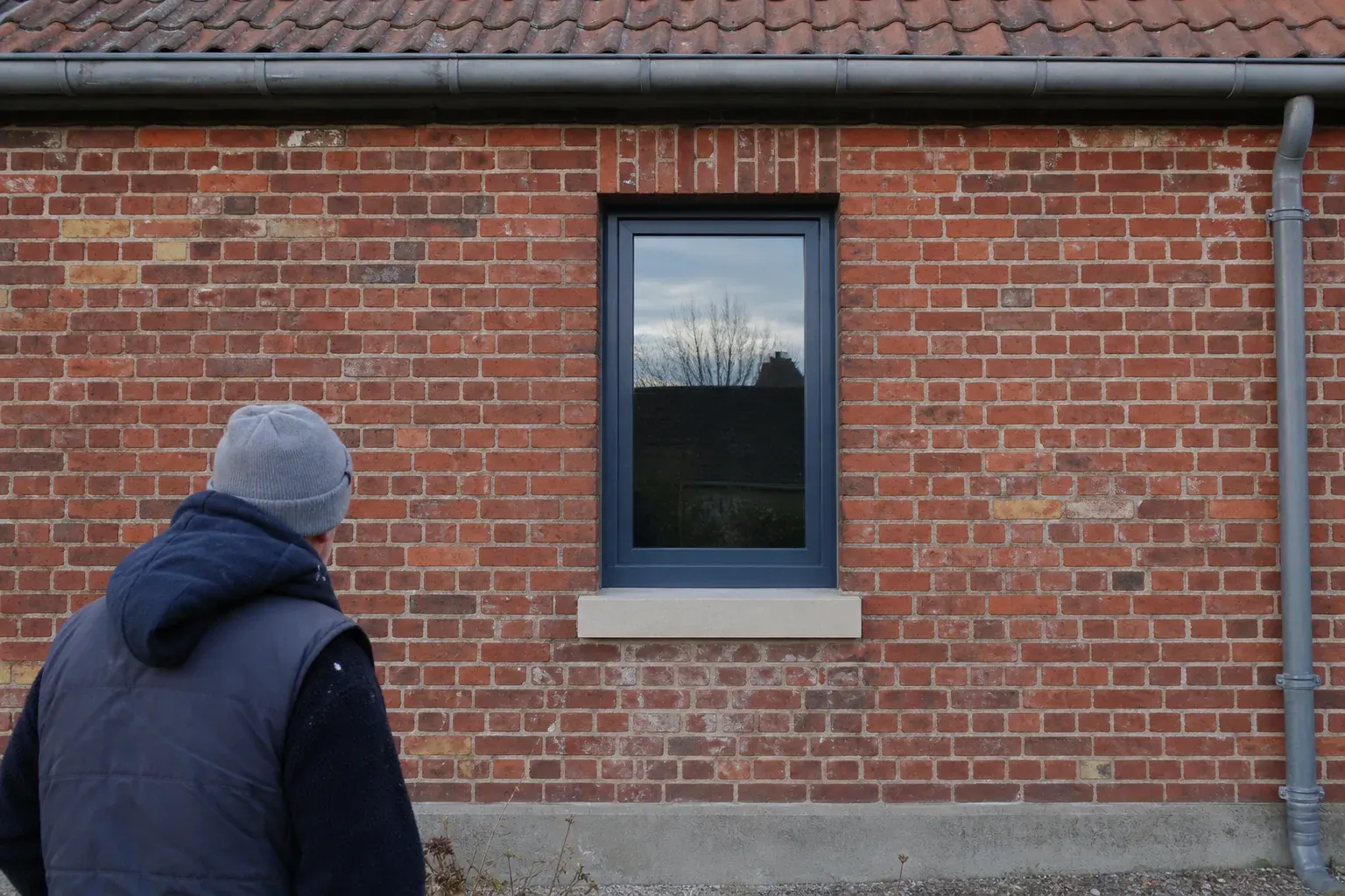 Fenêtre en aluminium neuve dans une façade de brique rouge, appui de fenêtre en pierre reconstituée