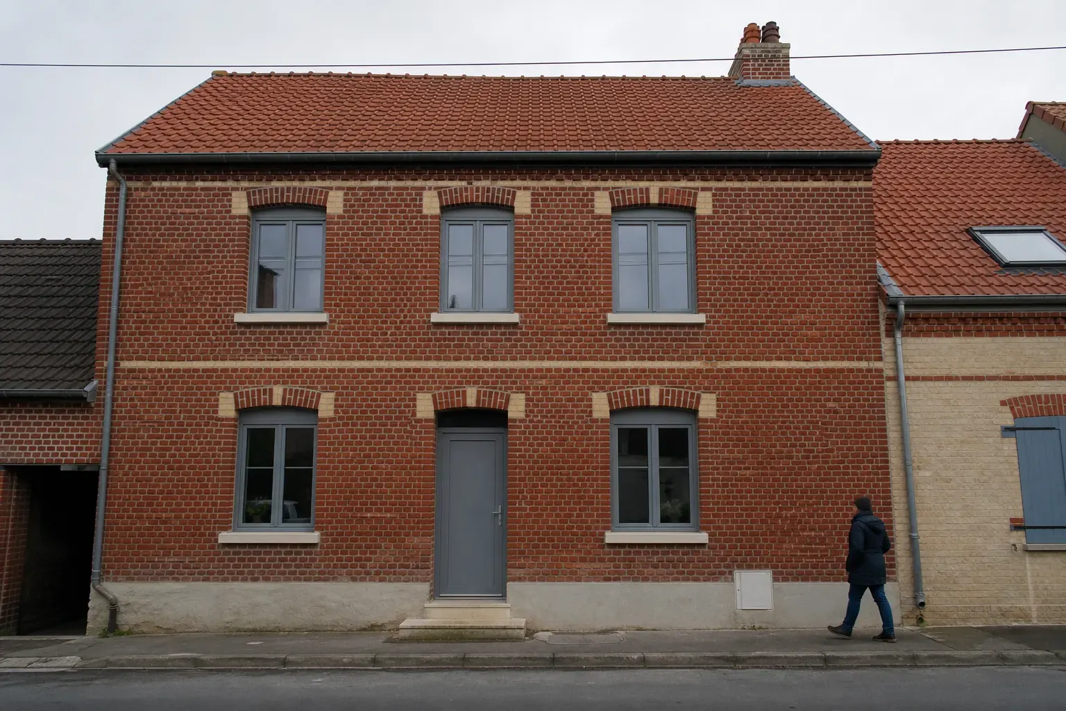 Fenêtres neuves en aluminium gris posées dans la façade en brique d’une maison du Pas-de-Calais, appui en pierre reconstituée, ciel voilé, photographie frontale documentaire