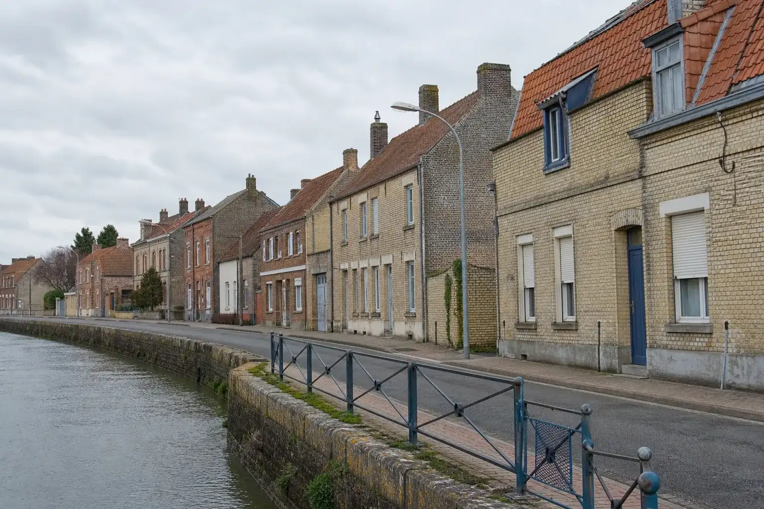 Rue résidentielle d’Audruicq dans le Pas-de-Calais, maisons de brique aux toitures en tuile, ciel couvert du littoral, photographie documentaire sans personne